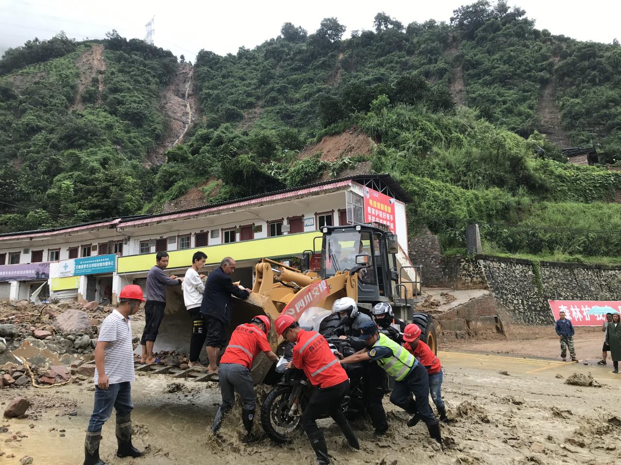 8月18日，搶險人員與民警幫助被困群眾的摩托車通過涉水路面.jpg